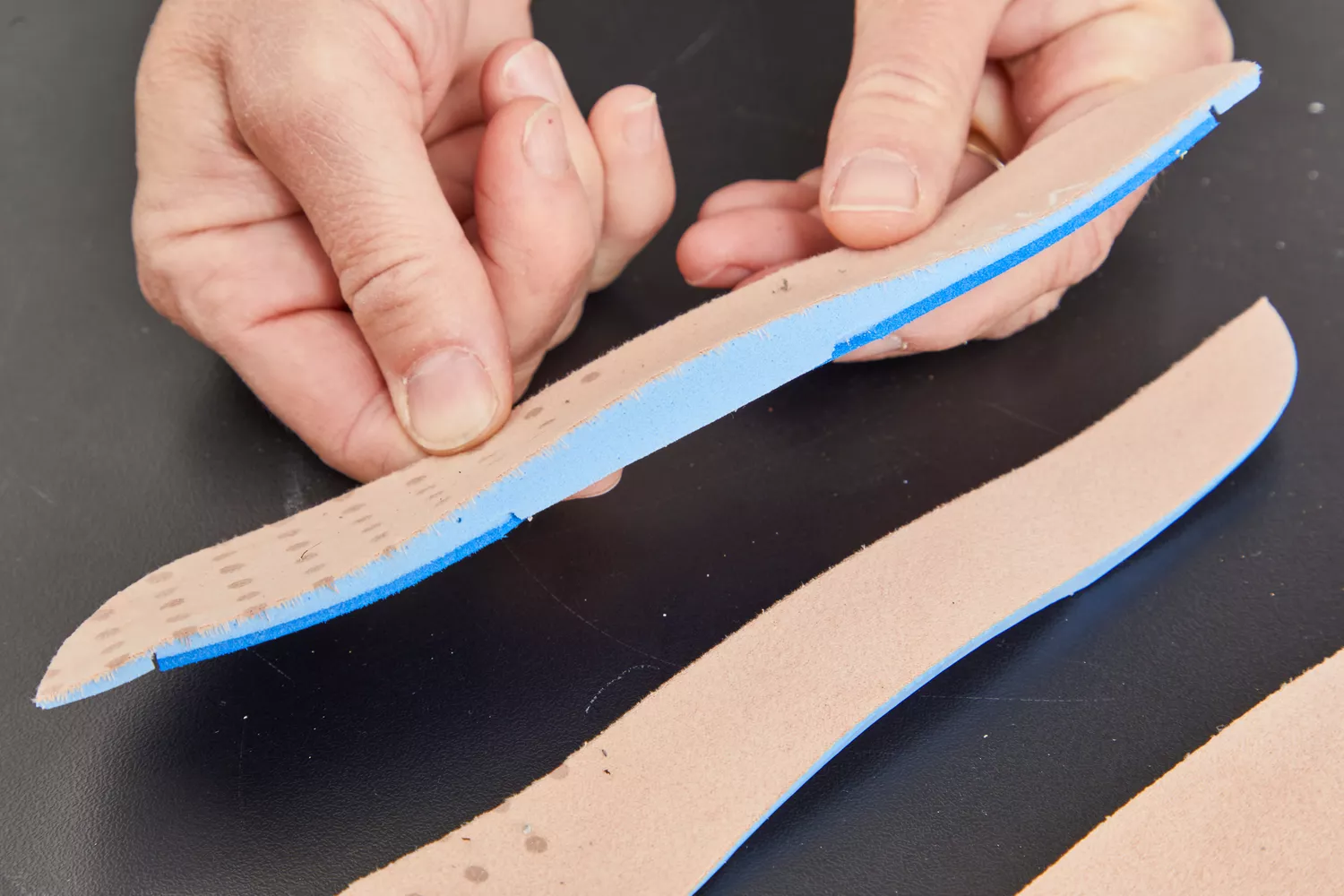 Hands holding half of a Vionic Slimfit Orthotic Insole