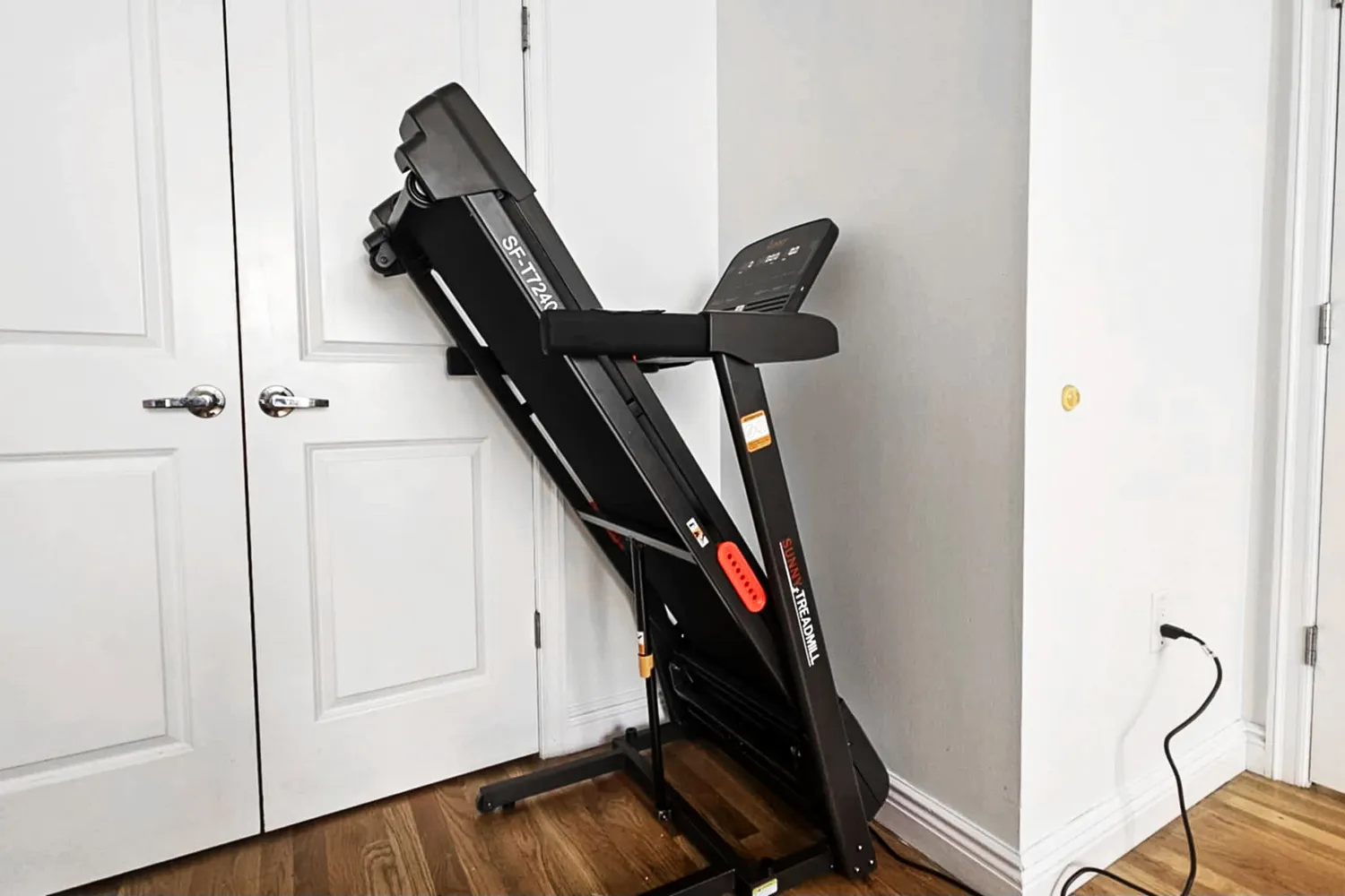 The Sunny Health & Fitness Active 400 Smart Auto Incline Wi-Fi Treadmill folded vertically against a wall