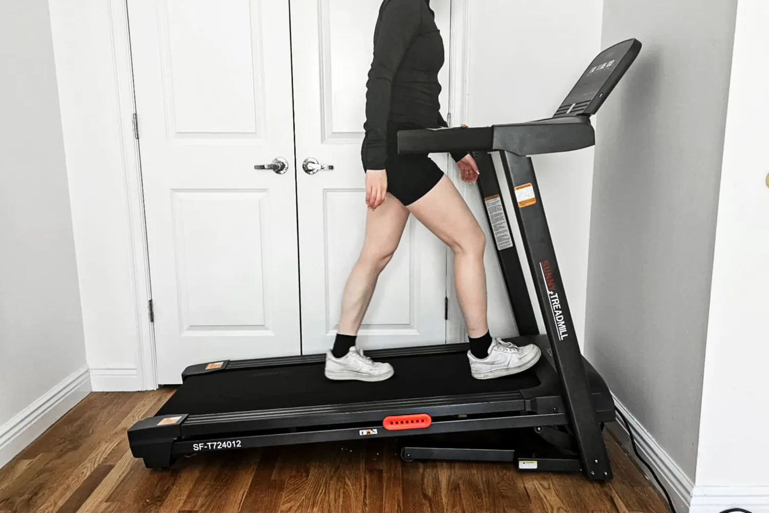 A side view of a person walking on the Sunny Health & Fitness Active 400 Smart Auto Incline Wi-Fi Treadmill