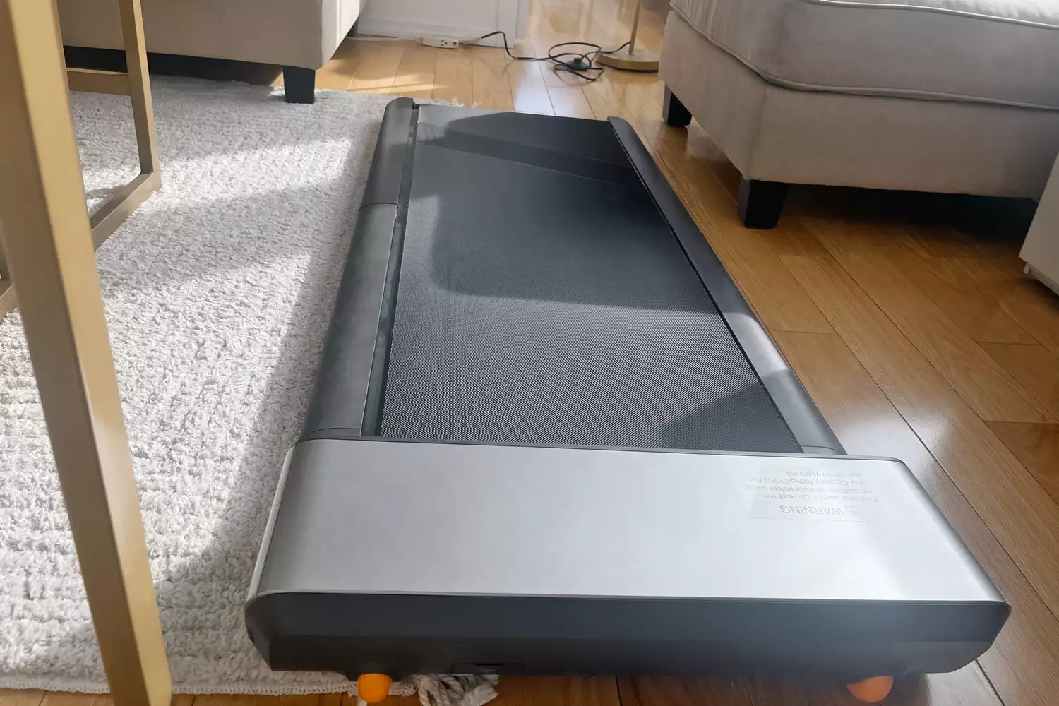 WalkingPad P1 Foldable Walking Treadmill on wood floor near chairs and sofa