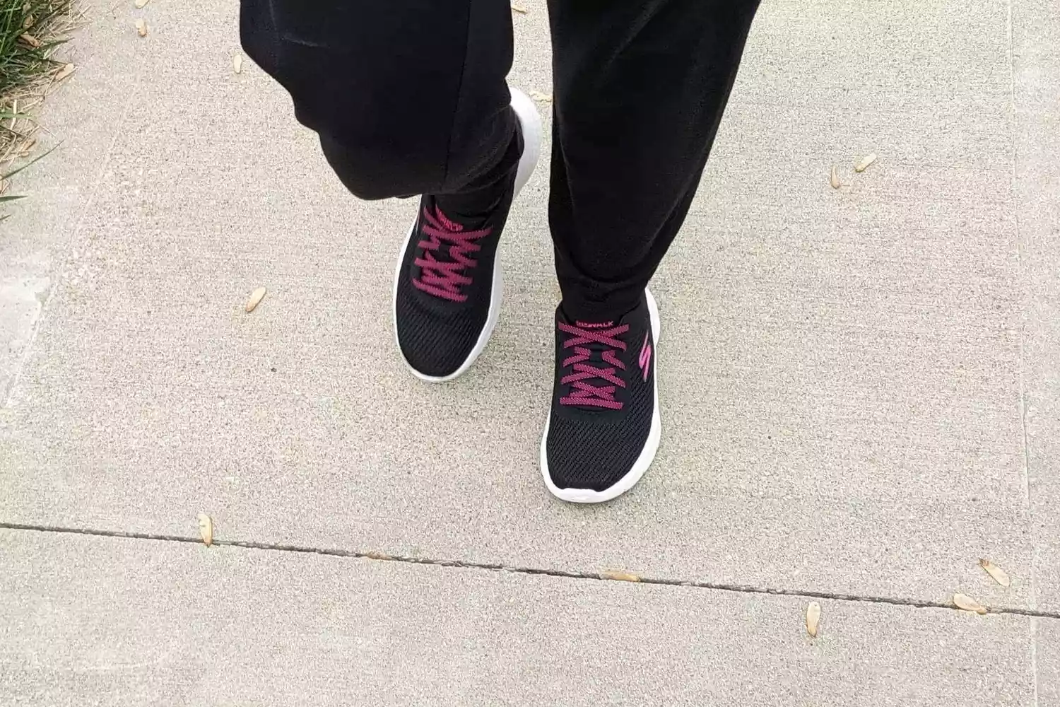 A closeup of a person wearing Skechers Go Walk Flex Alani Walking Shoes while walking on pavement