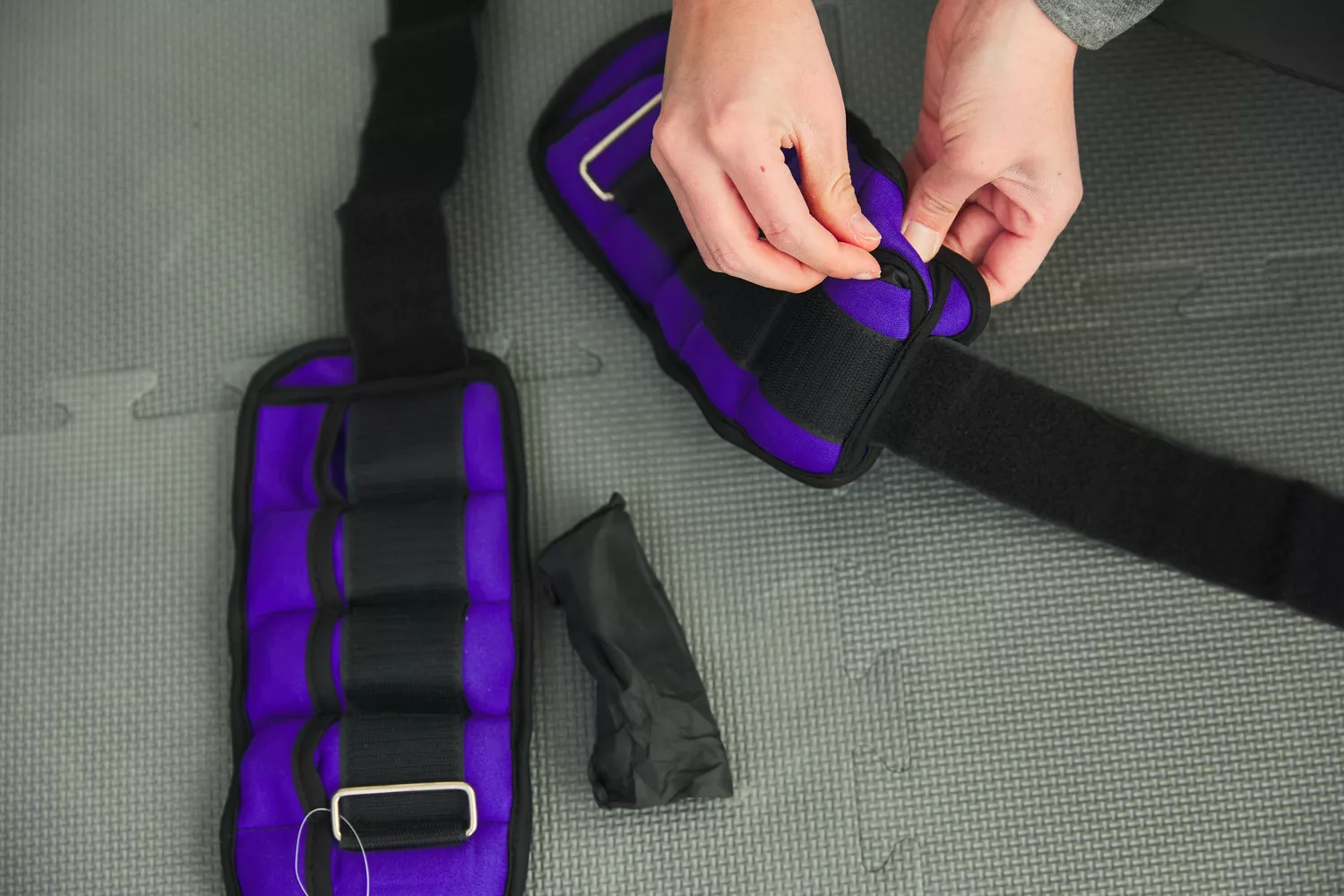 A person adds weight bags to the inserts on the Sportneer Ankle Weights