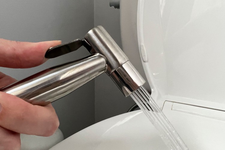 Hand spraying water from the Brondell CleanSpa Luxury Handheld Bidet Attachment into toilet