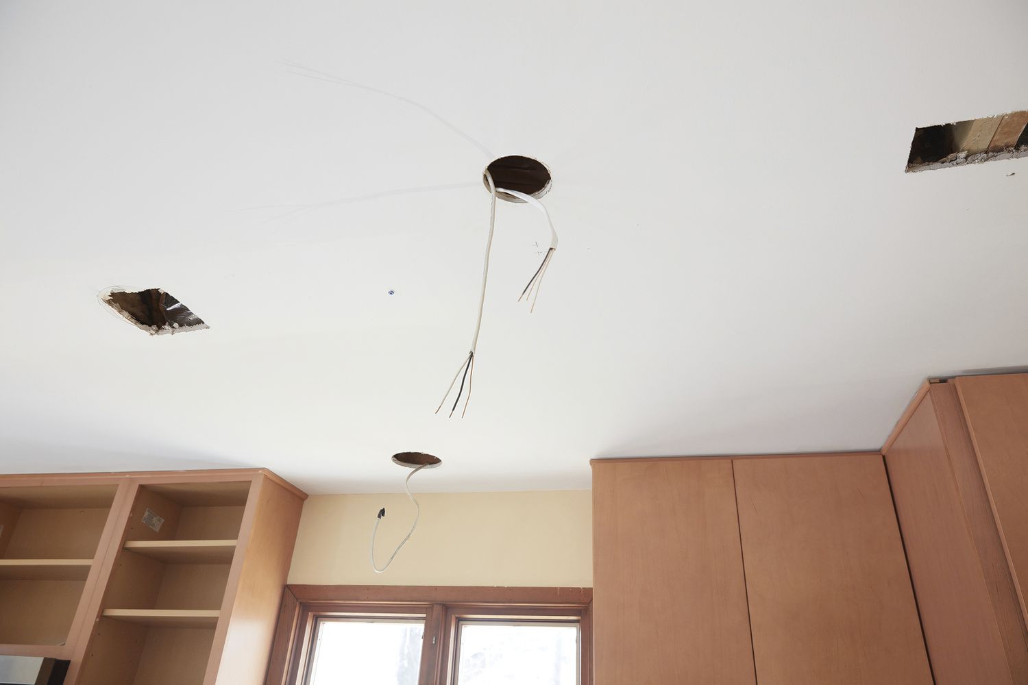 Ceiling with exposed recessed lighting holes and wires hanging