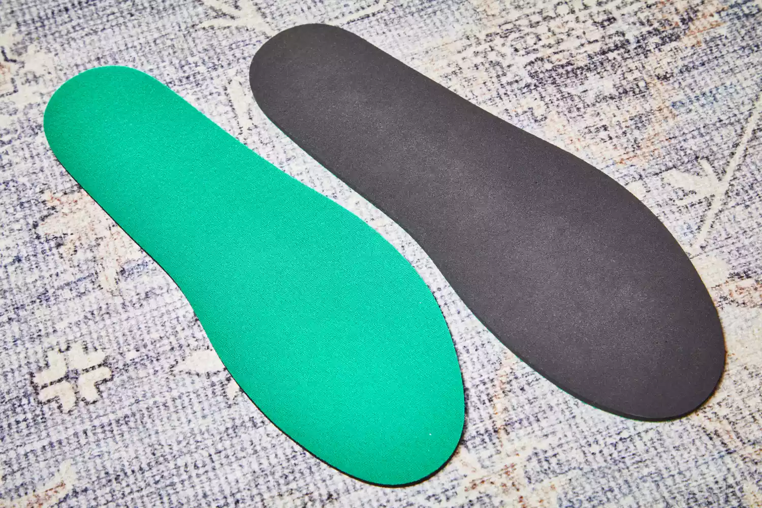 Both sides of the Spenco RX Comfort Insole displayed on carpet