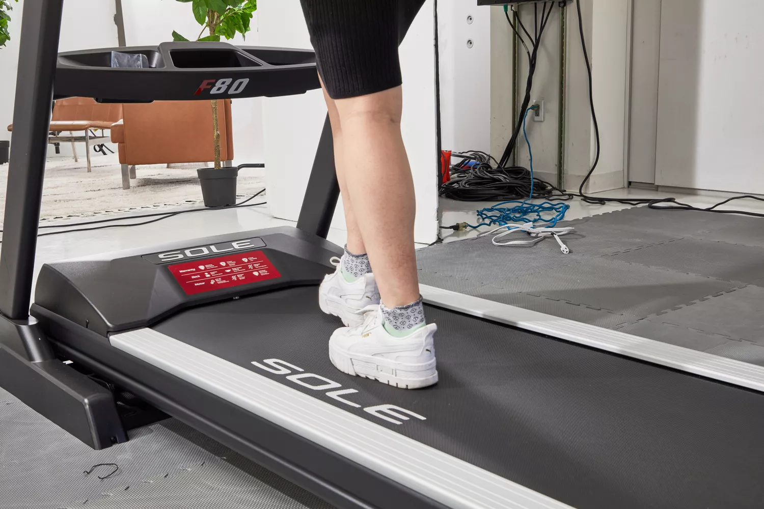 Person walking on a treadmill in white sneakers