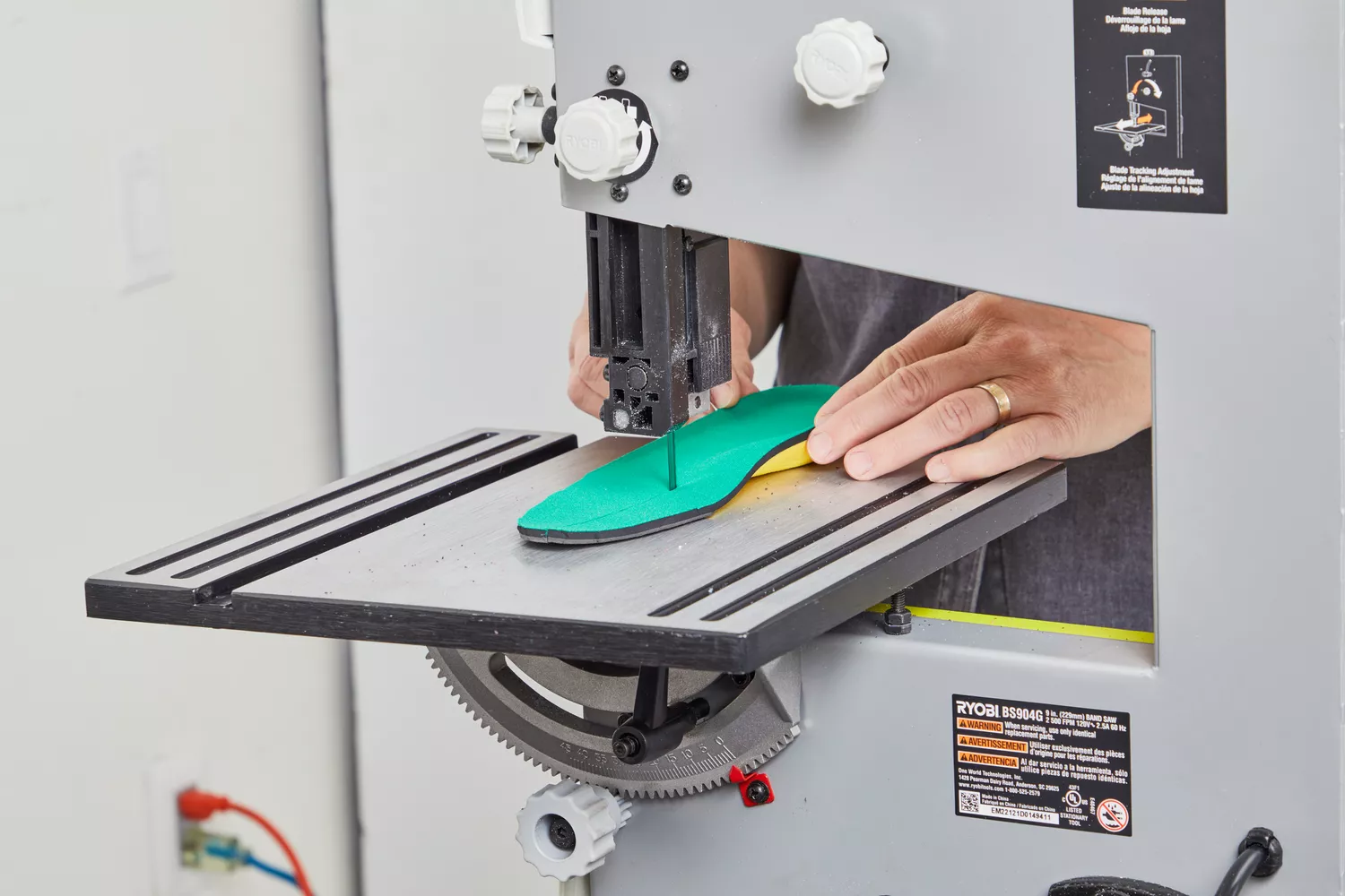Hands using a machine to cut a Spenco PolySorb Cross Trainer Insole in half