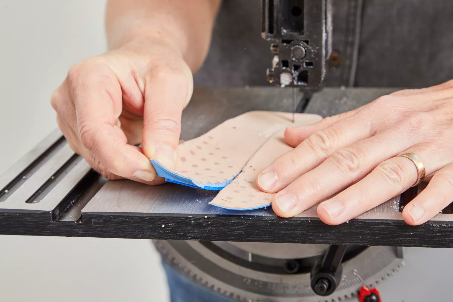 Hands cutting a Vionic Slimfit Orthotic Insoles in half with a band saw