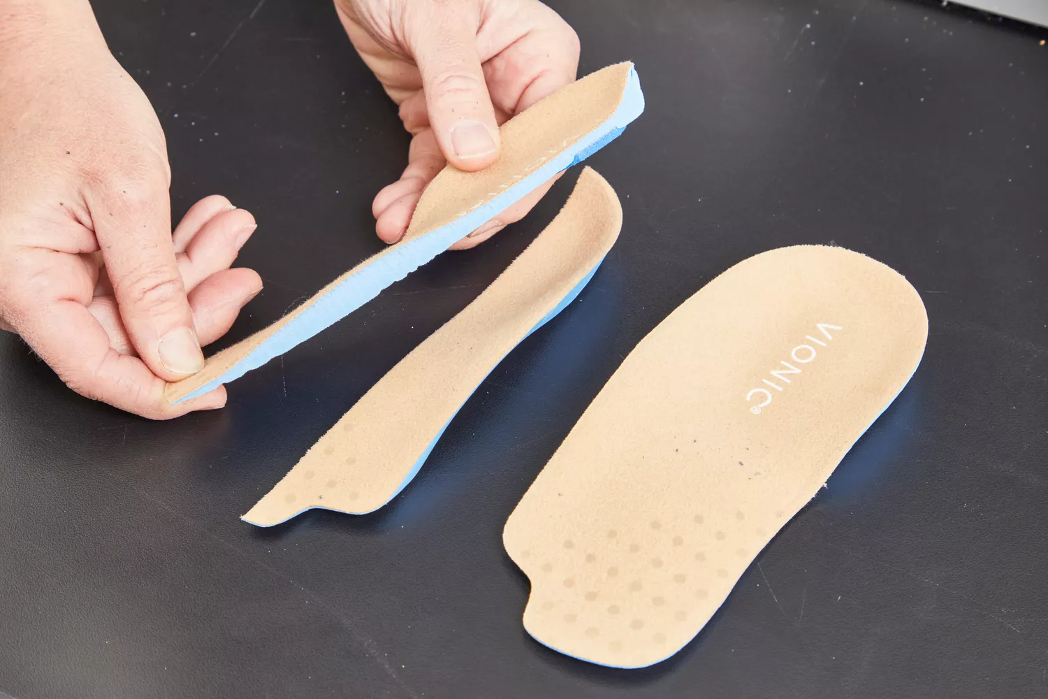 Hand holding half of a Vionic Slimfit Orthotic Insole