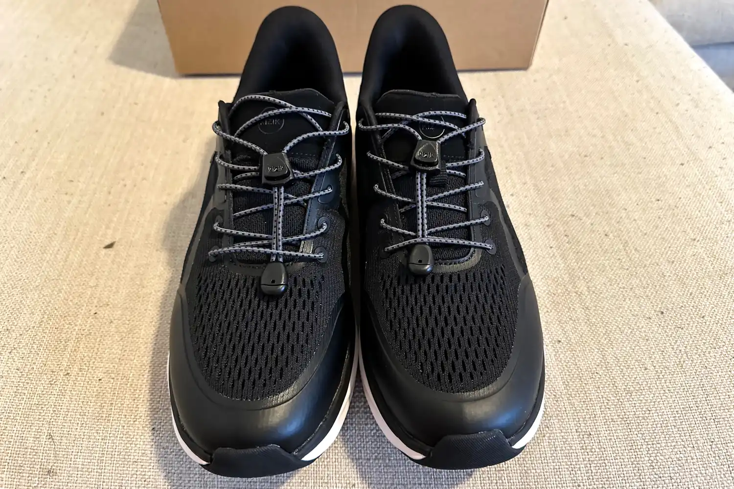 Two Kizik Men's London sneakers posed on fabric