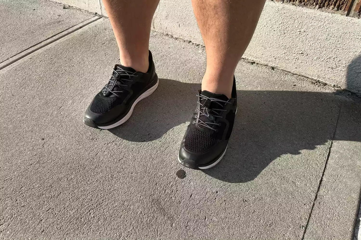 Two legs up close while wearing Kizik Men's London sneakers outdoors on concrete