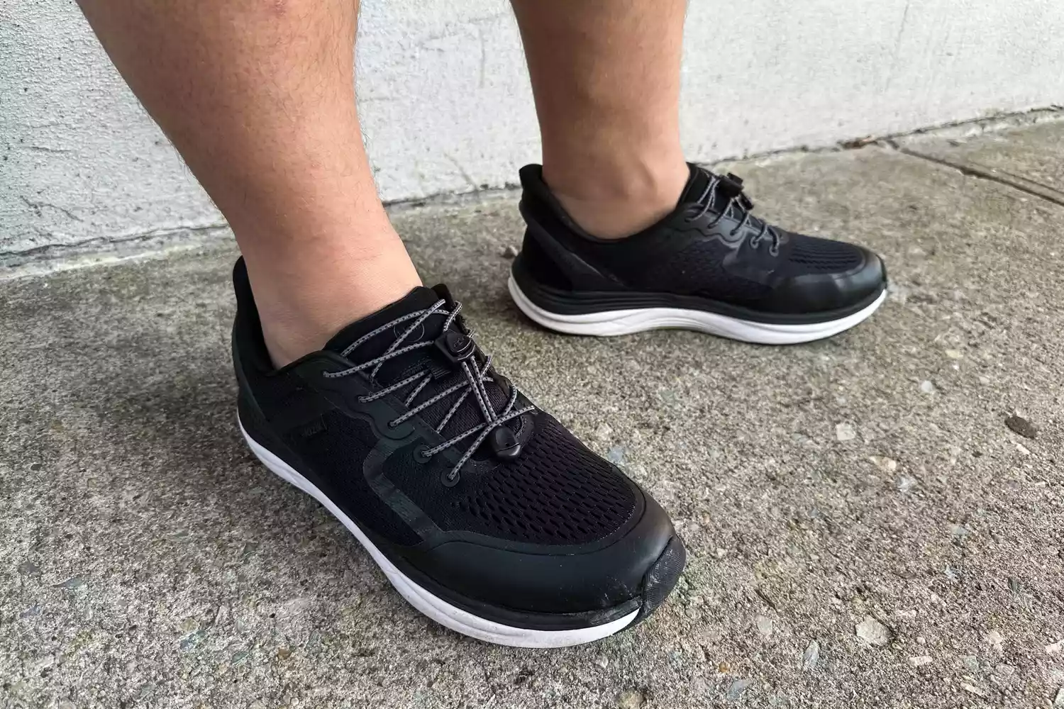 A close-up of legs wearing Kizik Men's London sneakers on concrete