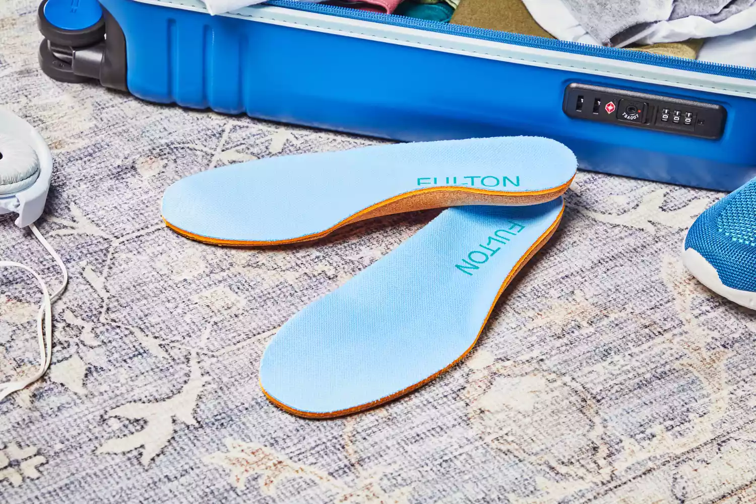 Fulton Athletic Insoles displayed on a rug next to a suitcase