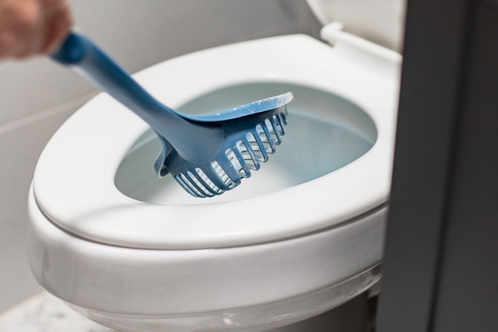 Blue cat litter scoop over toilet bowl