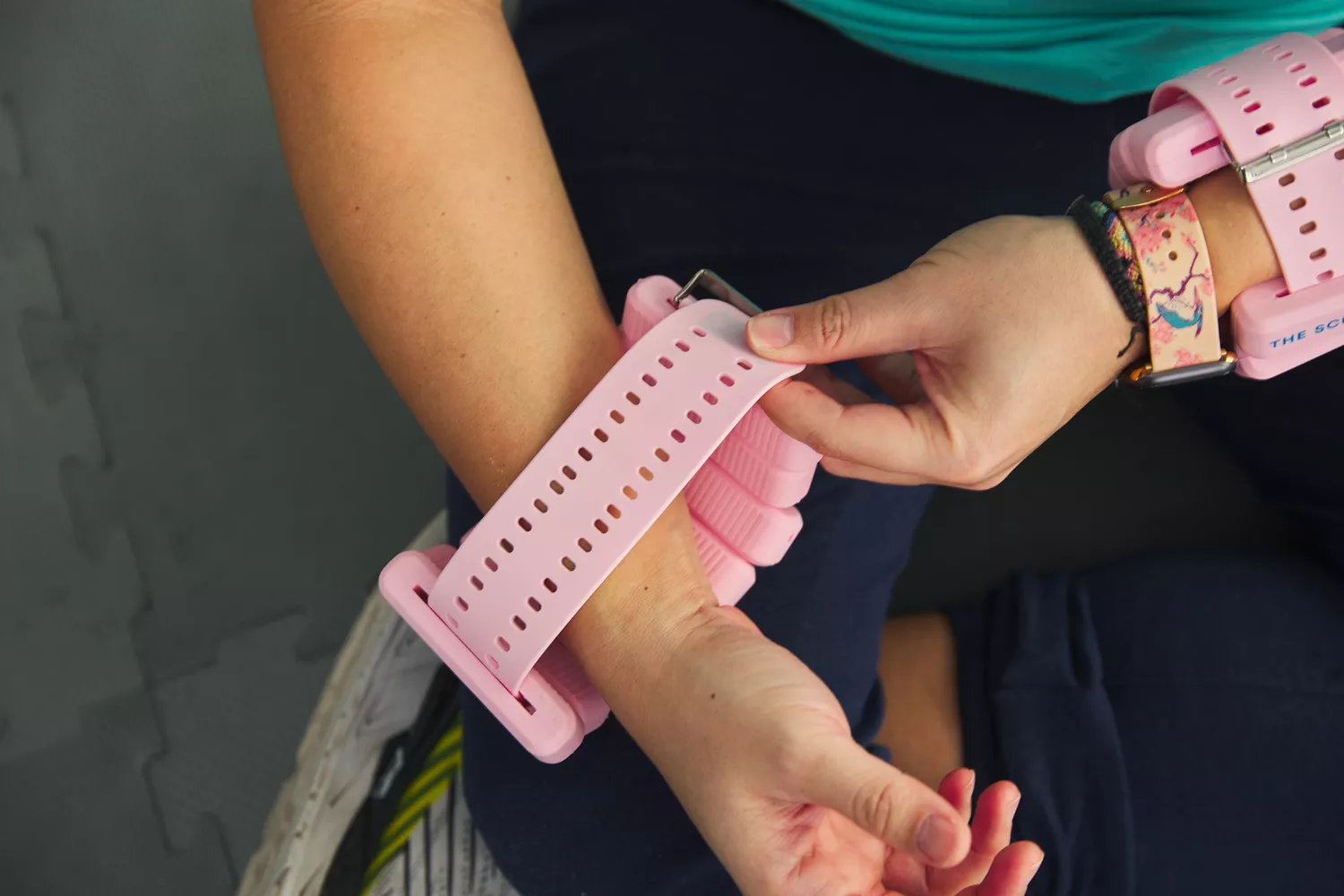 A person fastens pink The Sculpt Society 2 LB Weight around their wrist