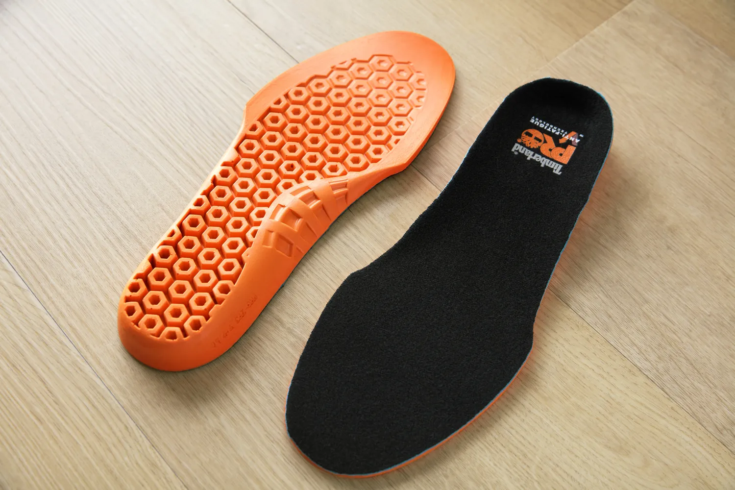 Top and bottom of Timberland Pro Anti-Fatigue Technology Insoles displayed on a wood floor