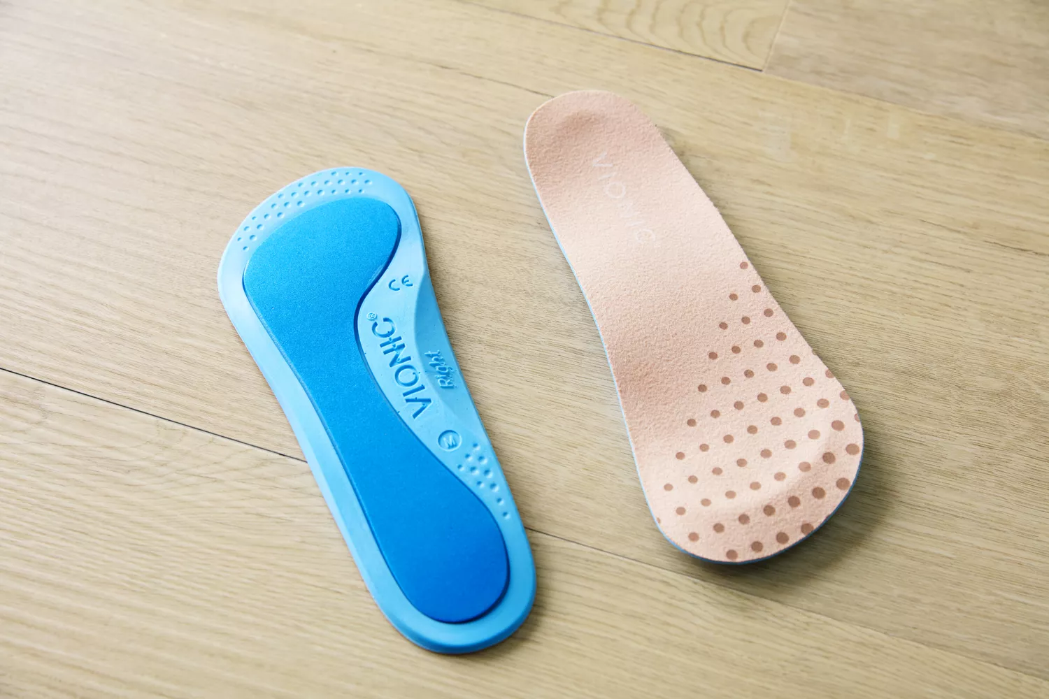 Top and bottom of Vionic Slimfit Orthotic Insoles displayed on a wood floor
