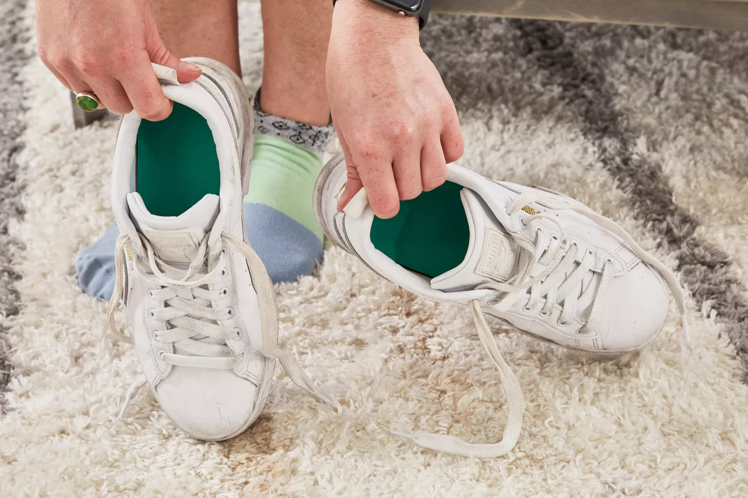 Hand holding white sneakers showing the Spenco PolySorb Cross Trainer Insoles inside