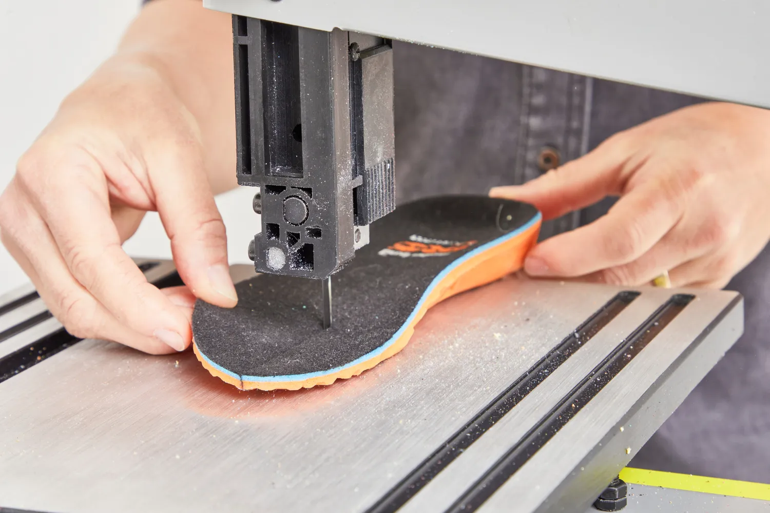 Hands cutting a Timberland Pro Anti-Fatigue Technology Insole in half on a band saw