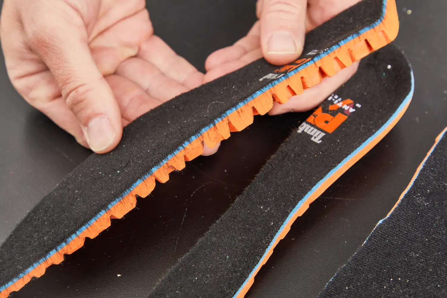 Hands holding half of a Timberland Pro Anti-Fatigue Technology Insole