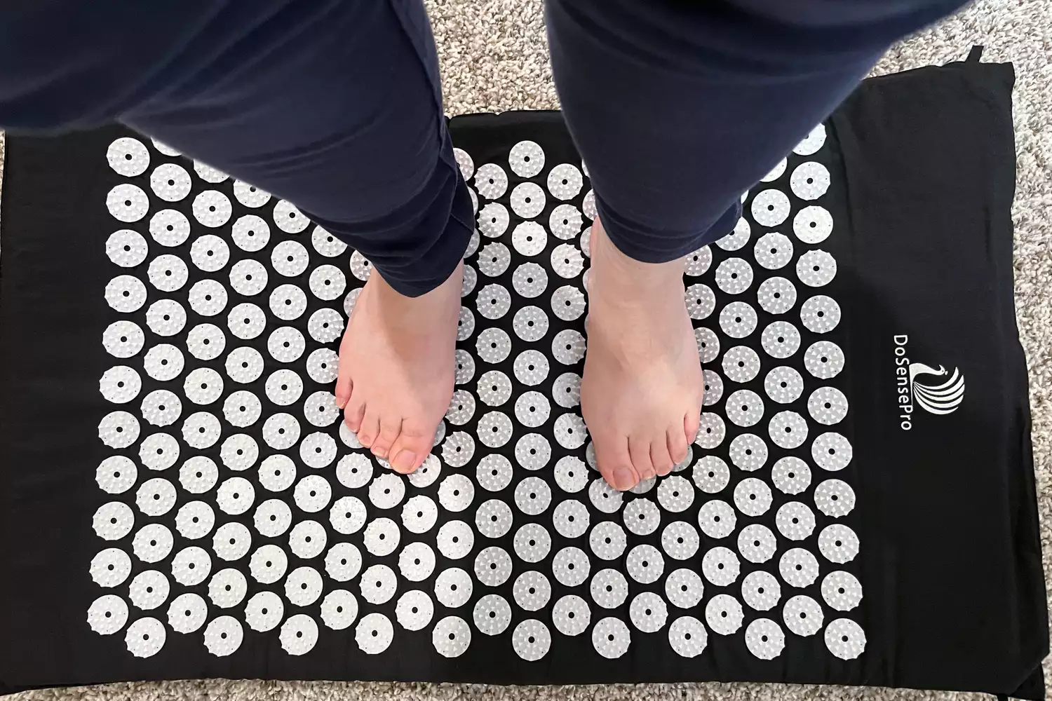 Above view of bare feet standing on the DoSensePro Acupressure Mat