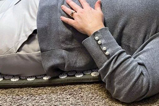 Side view closeup of woman laying on the Gaiam Acupressure Mat and Pillow Set