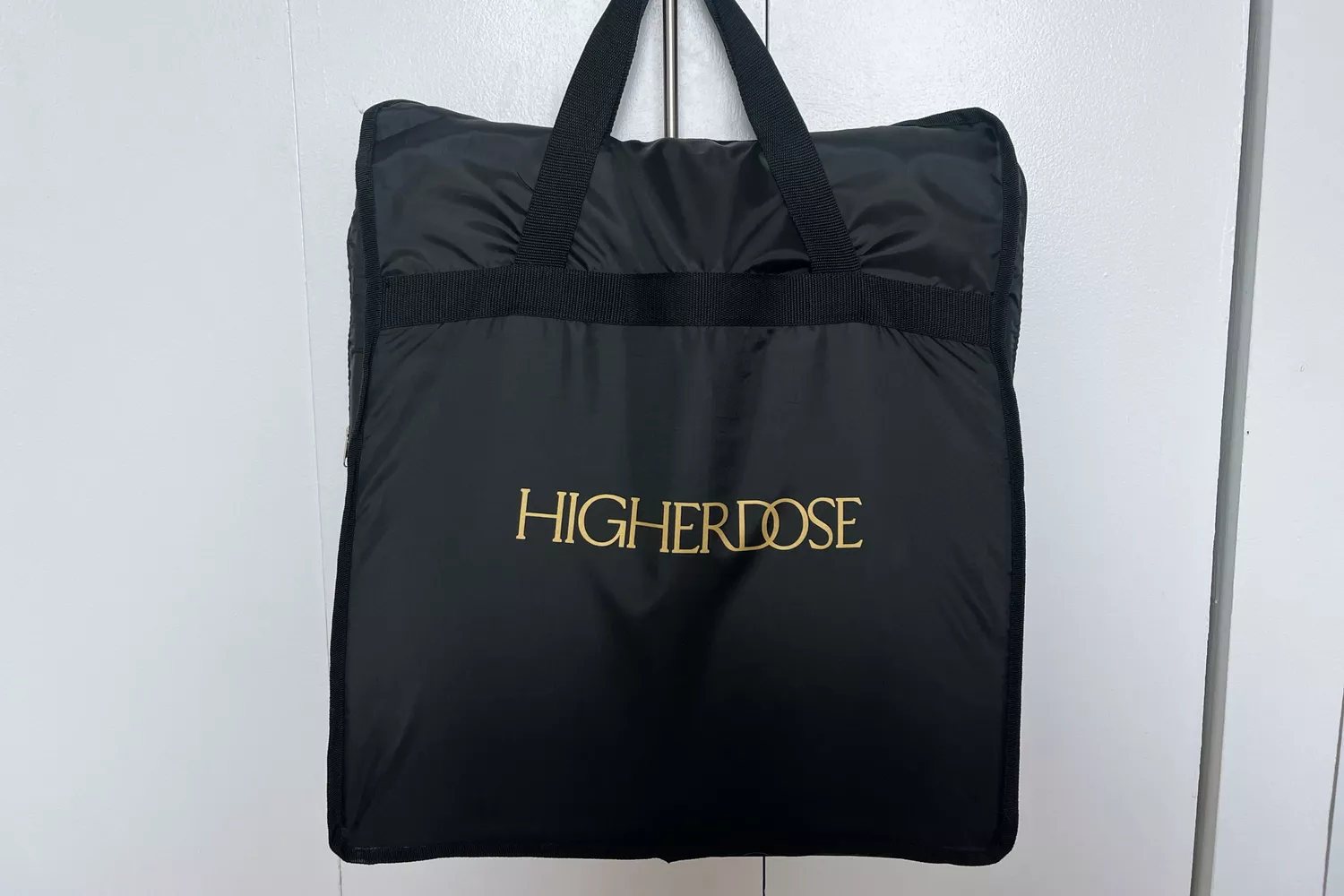 Higher Dose Infrared PEMF Go Mat inside black bag with handle hanging on white door