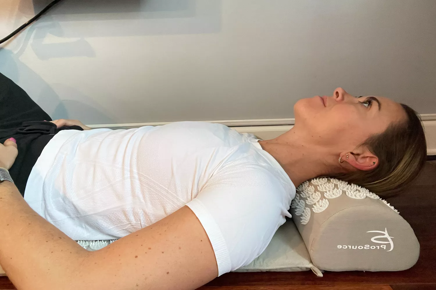 Woman laying back on the ProsourceFit Acupressure Mat and Pillow Set