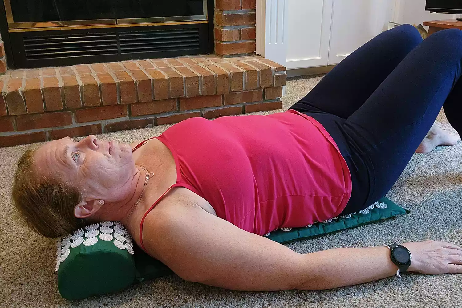Woman laying down on the Sivan Back and Neck Pain Relief Acupressure Mat and Pillow Set