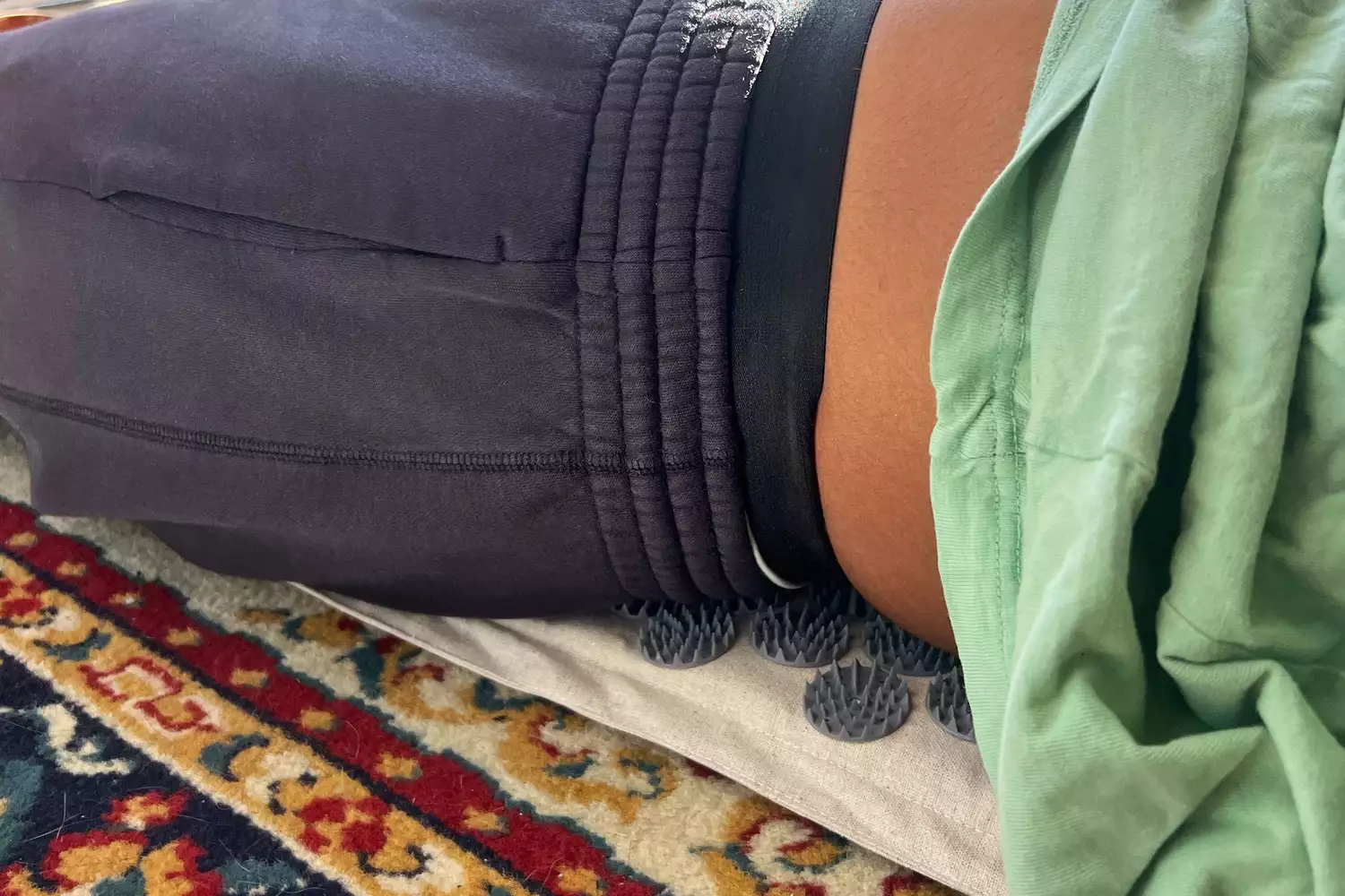 Side view closeup of woman laying on the WTHN Acupressure Mat Set