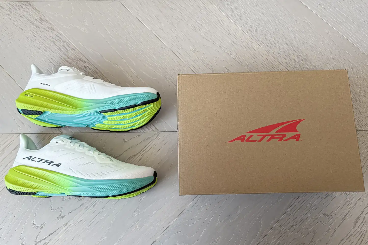 A side view of the Altra Men's Experience Flow 2 Sneakers next to a branded box