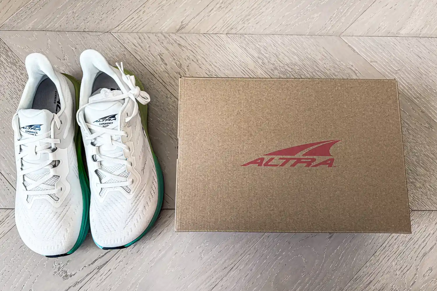 A pair of Altra Men's Experience Flow 2 Sneakers next to a branded box