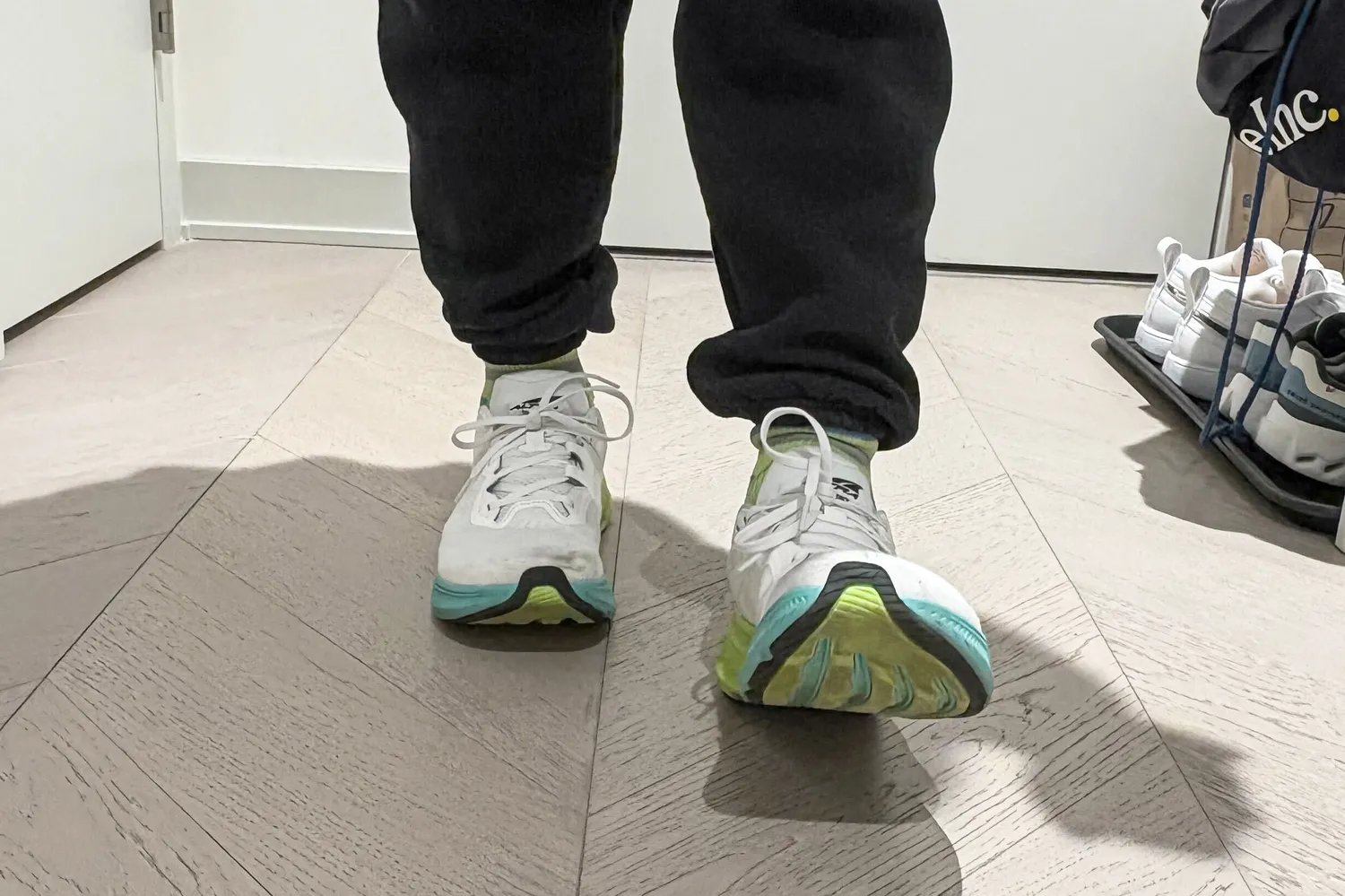 A person walks across a wooden floor while wearing the Altra Men's Experience Flow 2 Sneakers