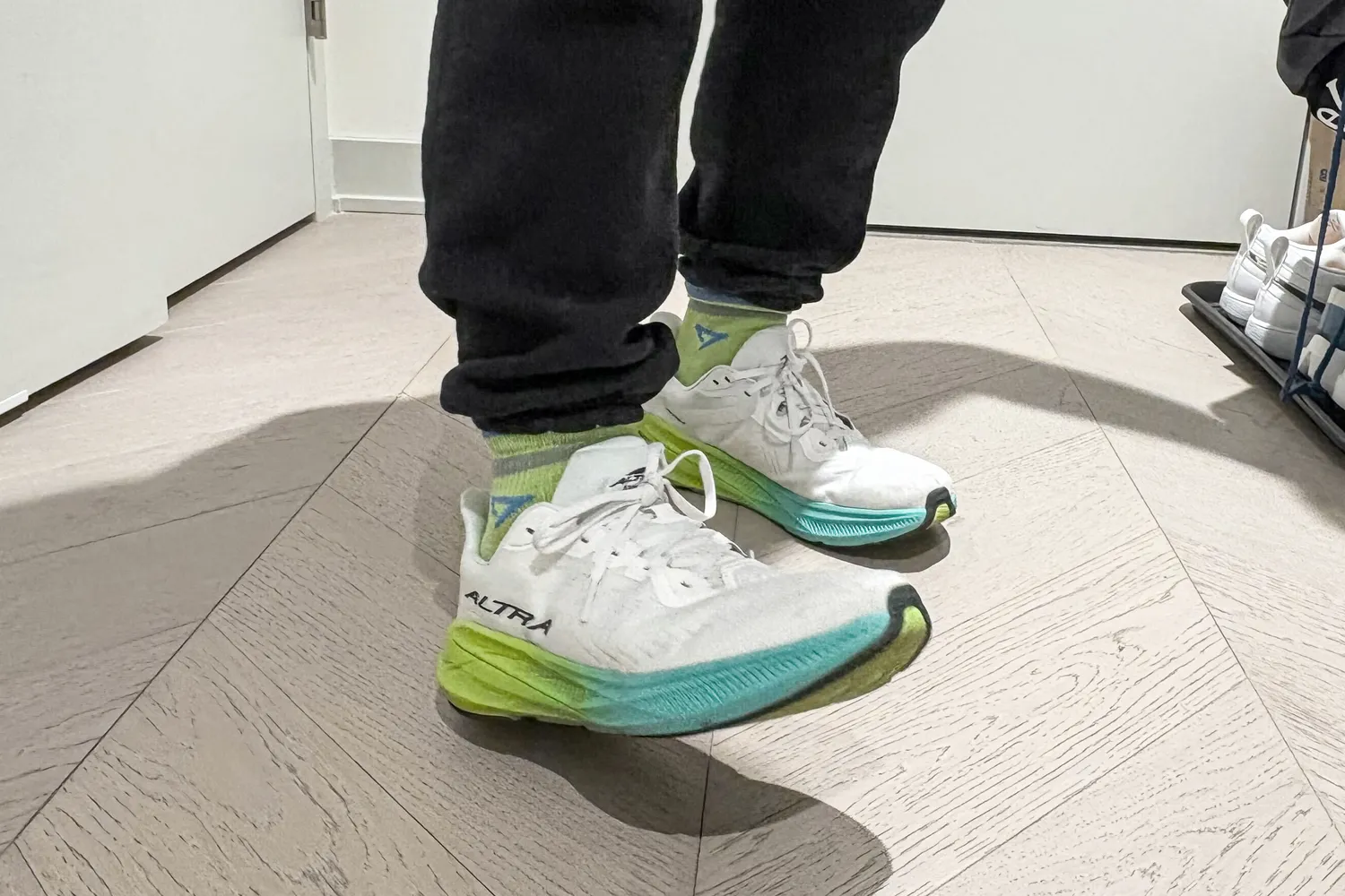 A person wears the Altra Men's Experience Flow 2 Sneakers while standing inside