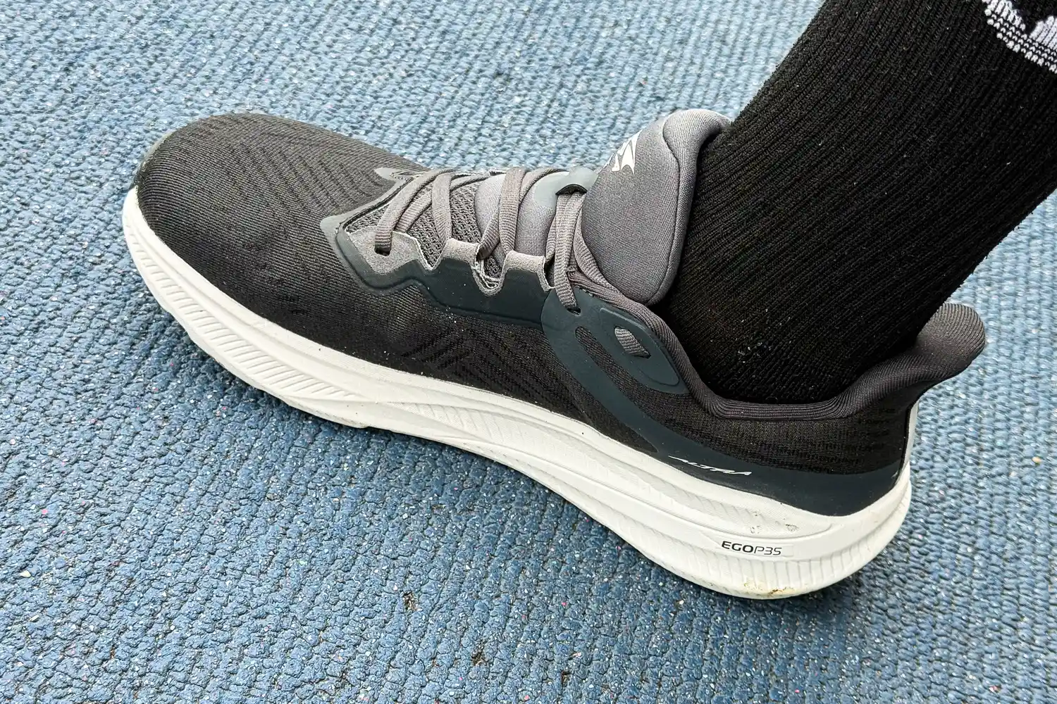 A person wears the Altra Men's Experience Flow 2 Sneakers inside on carpet