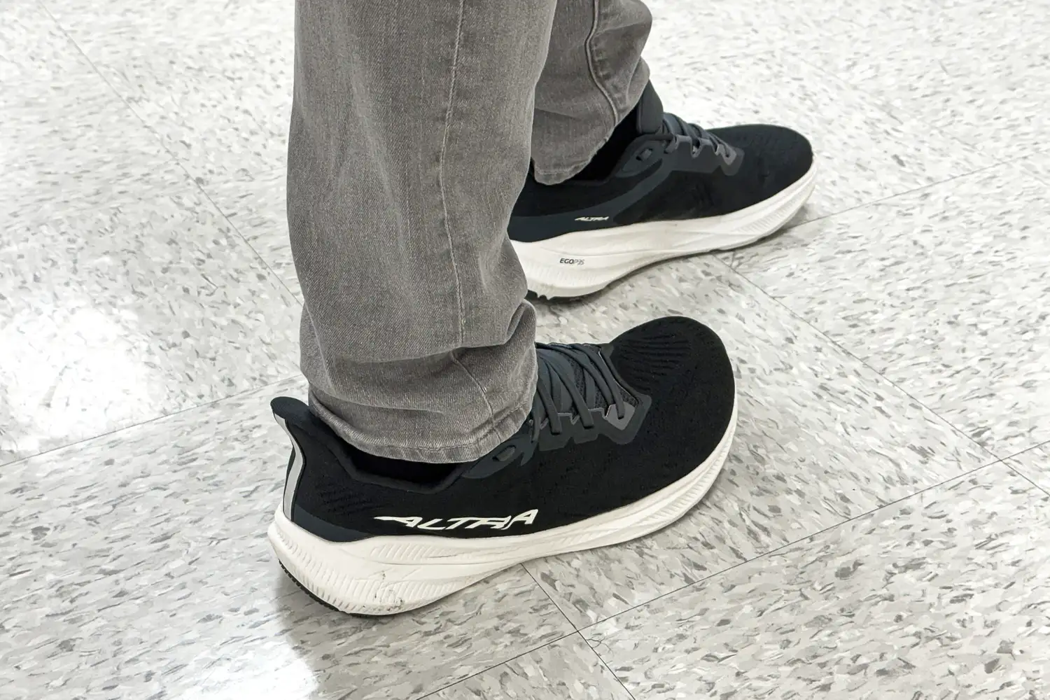 A person wears the Altra Men's Experience Flow 2 Sneakers while walking on a tile floor