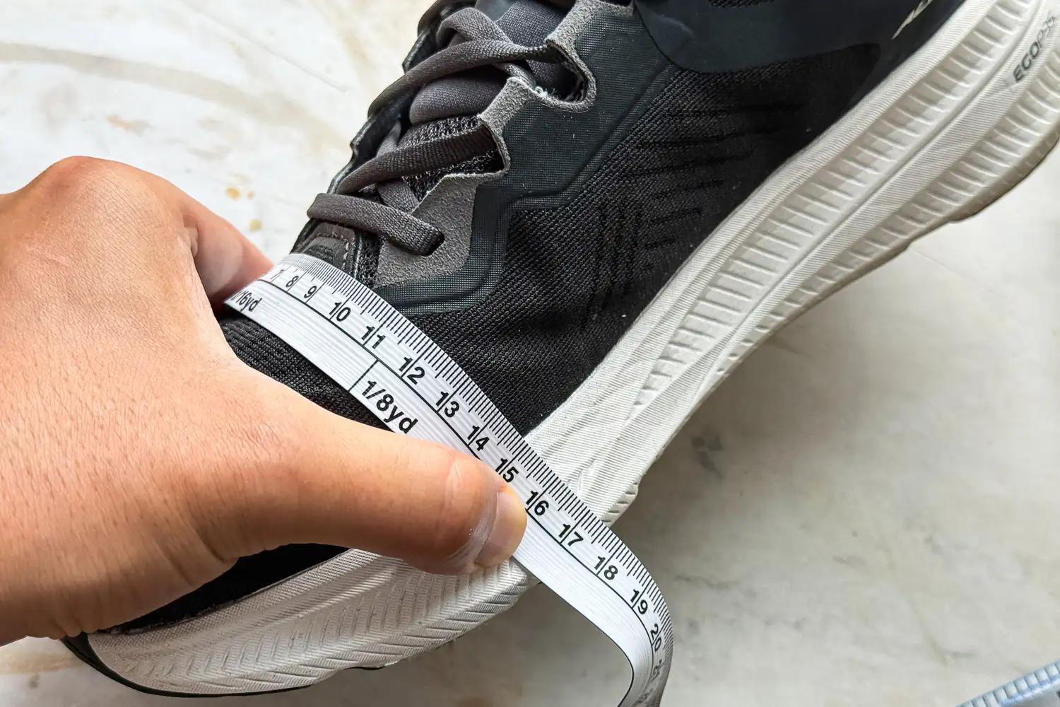 A measuring tape is wrapped around the widest part of the Altra Men's Experience Flow 2 Sneaker