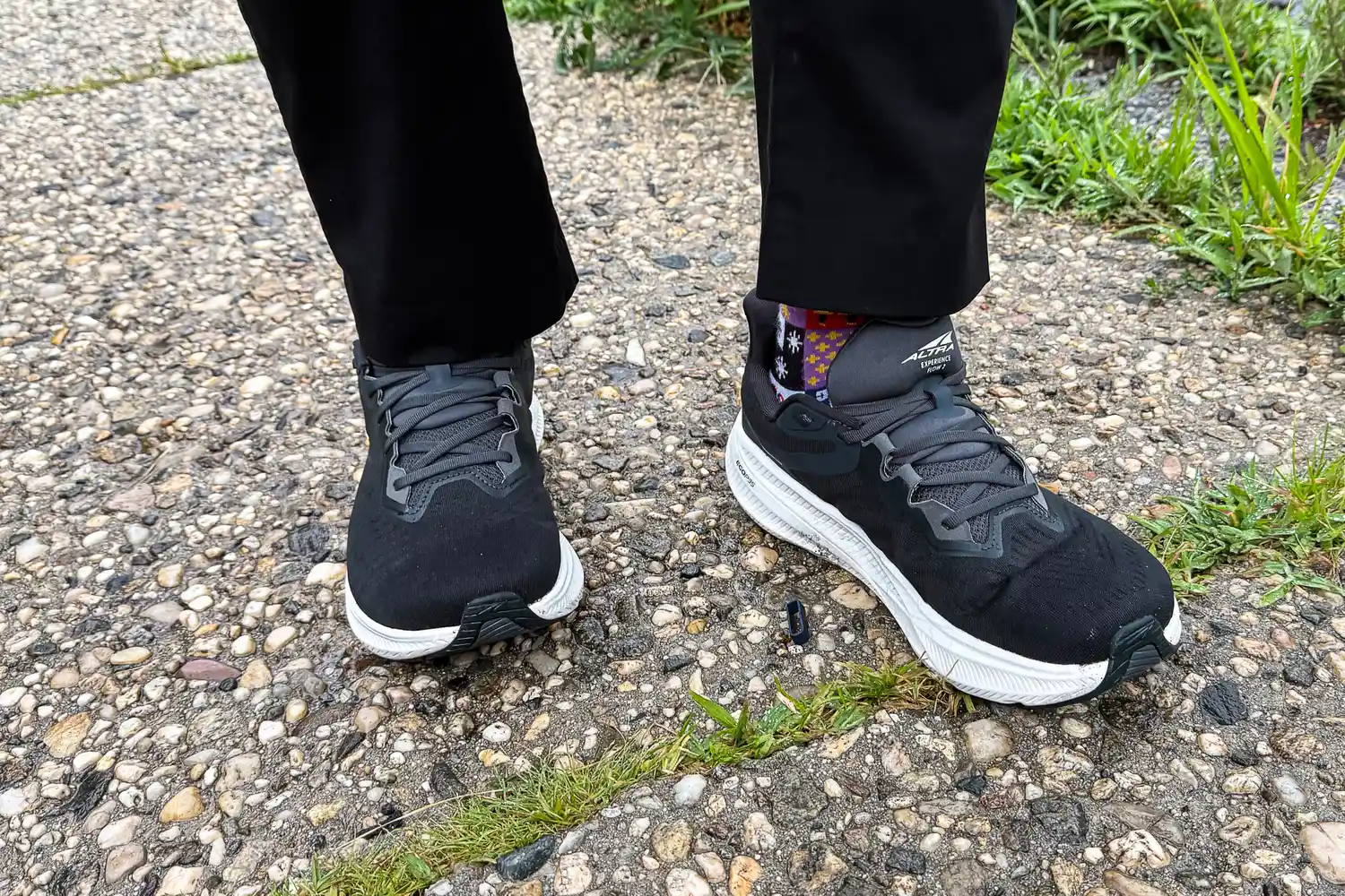 A person wears the Altra Men's Experience Flow 2 Sneakers on a pebbled path
