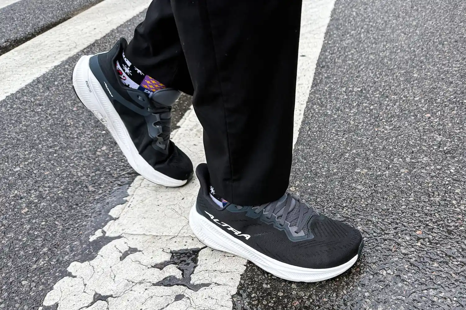 A person wears the Altra Men's Experience Flow 2 Sneakers while walking across the crosswalk