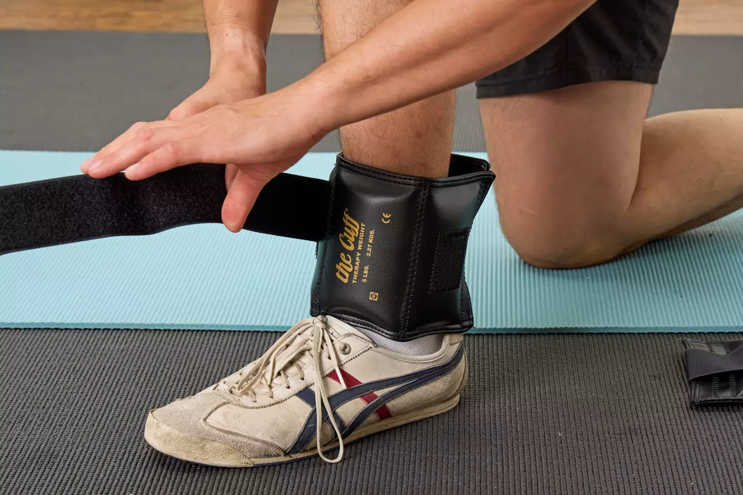 A person tightens the strap on the The Cuff Original Adjustable Ankle and Wrist Weight