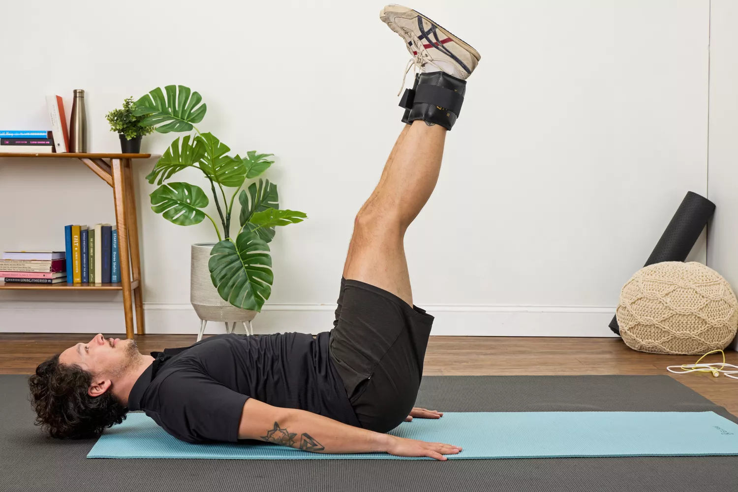 A person wears the The Cuff Original Adjustable Ankle and Wrist Weights on their legs while doing leg lifts