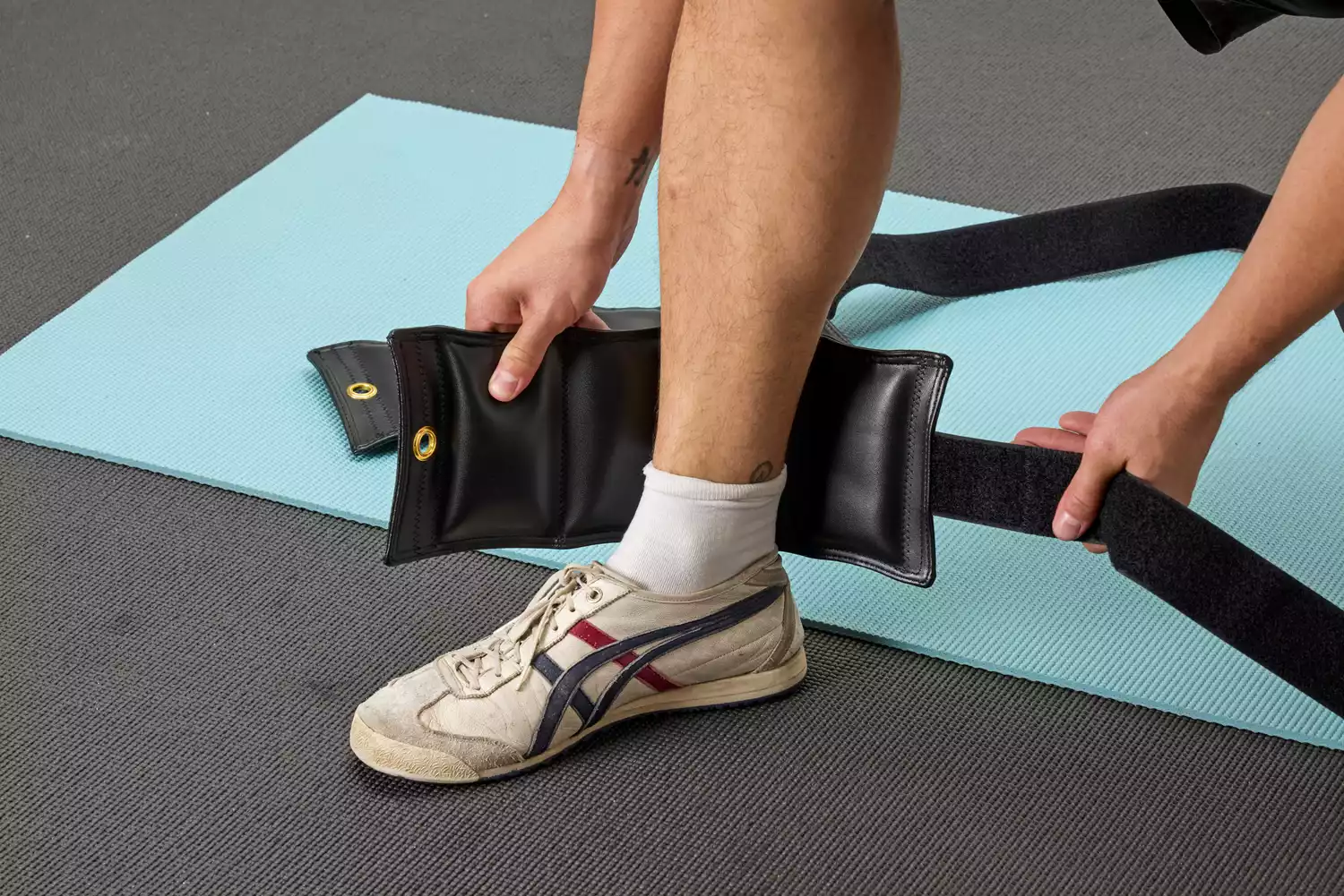 A person attaches the The Cuff Original Adjustable Ankle and Wrist Weight to their ankle