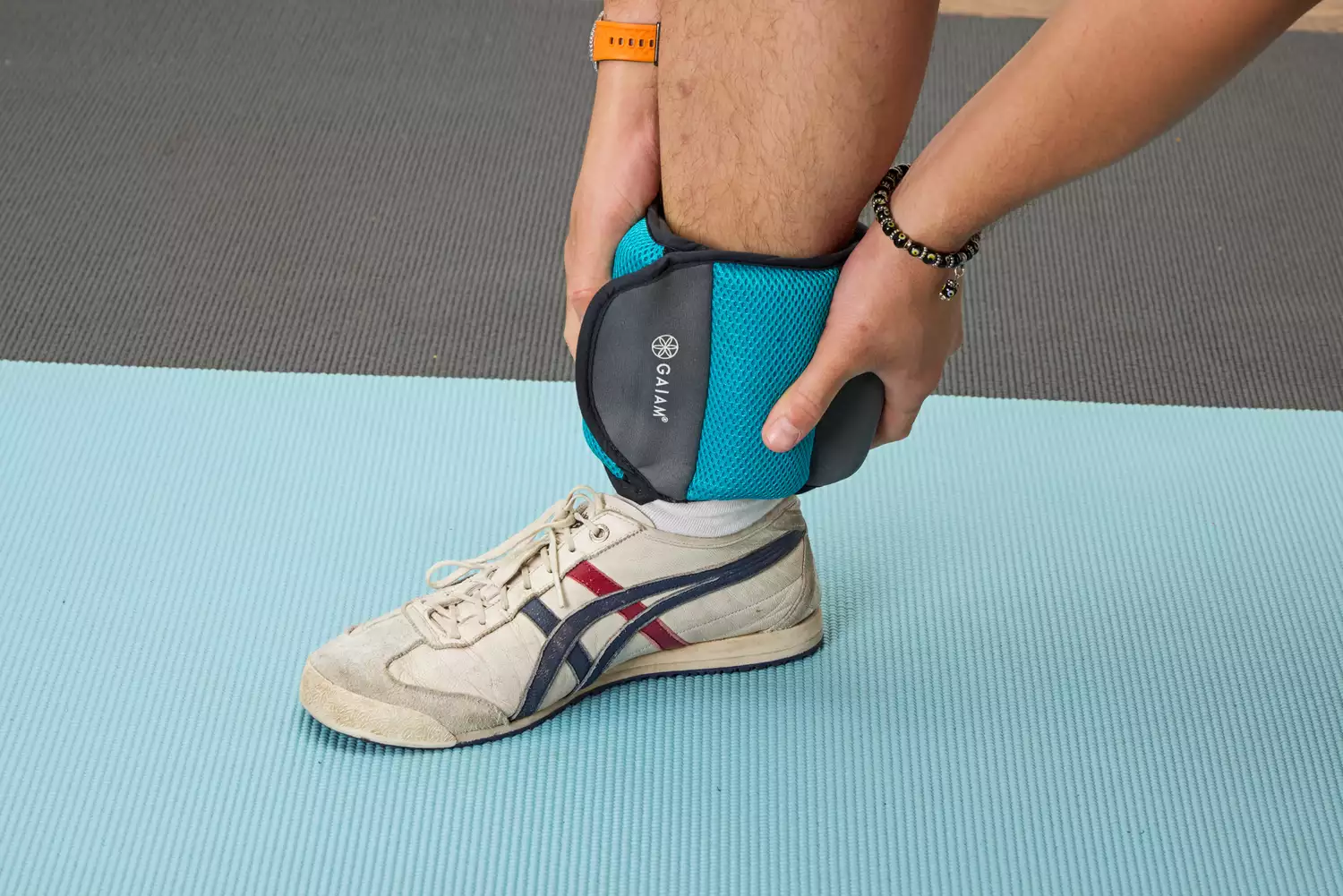 A person wears the Gaiam Fitness Ankle Weights on their ankle
