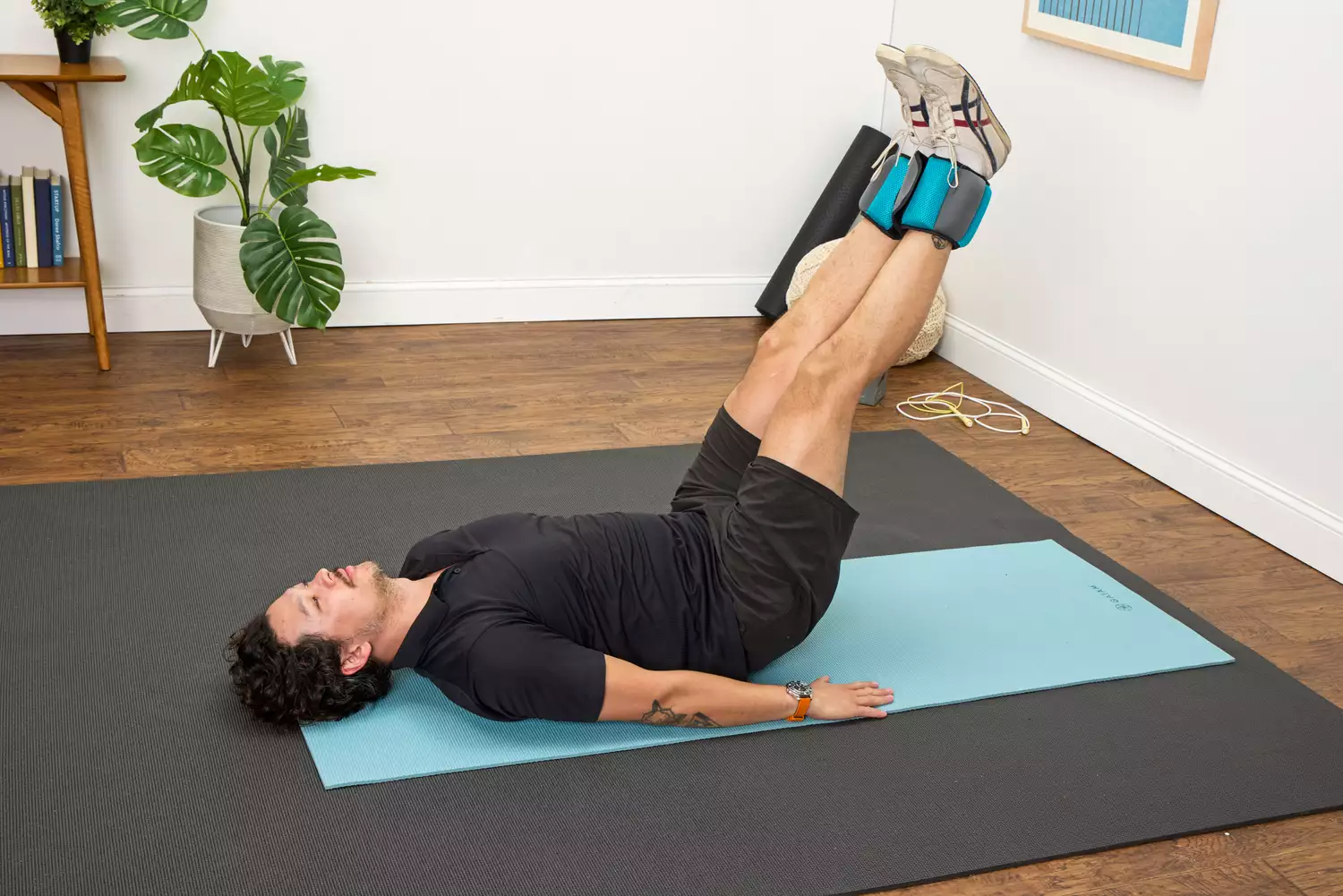 A person does leg lifts while wearing the Gaiam Fitness Ankle Weights