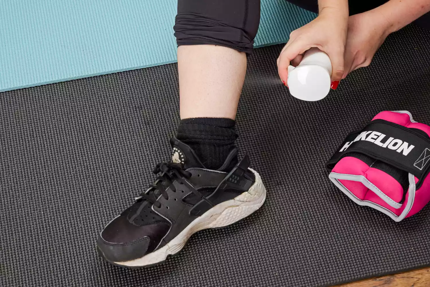 A person sprays water into their ankle before putting on the Henkelion Adjustable Ankle Weights