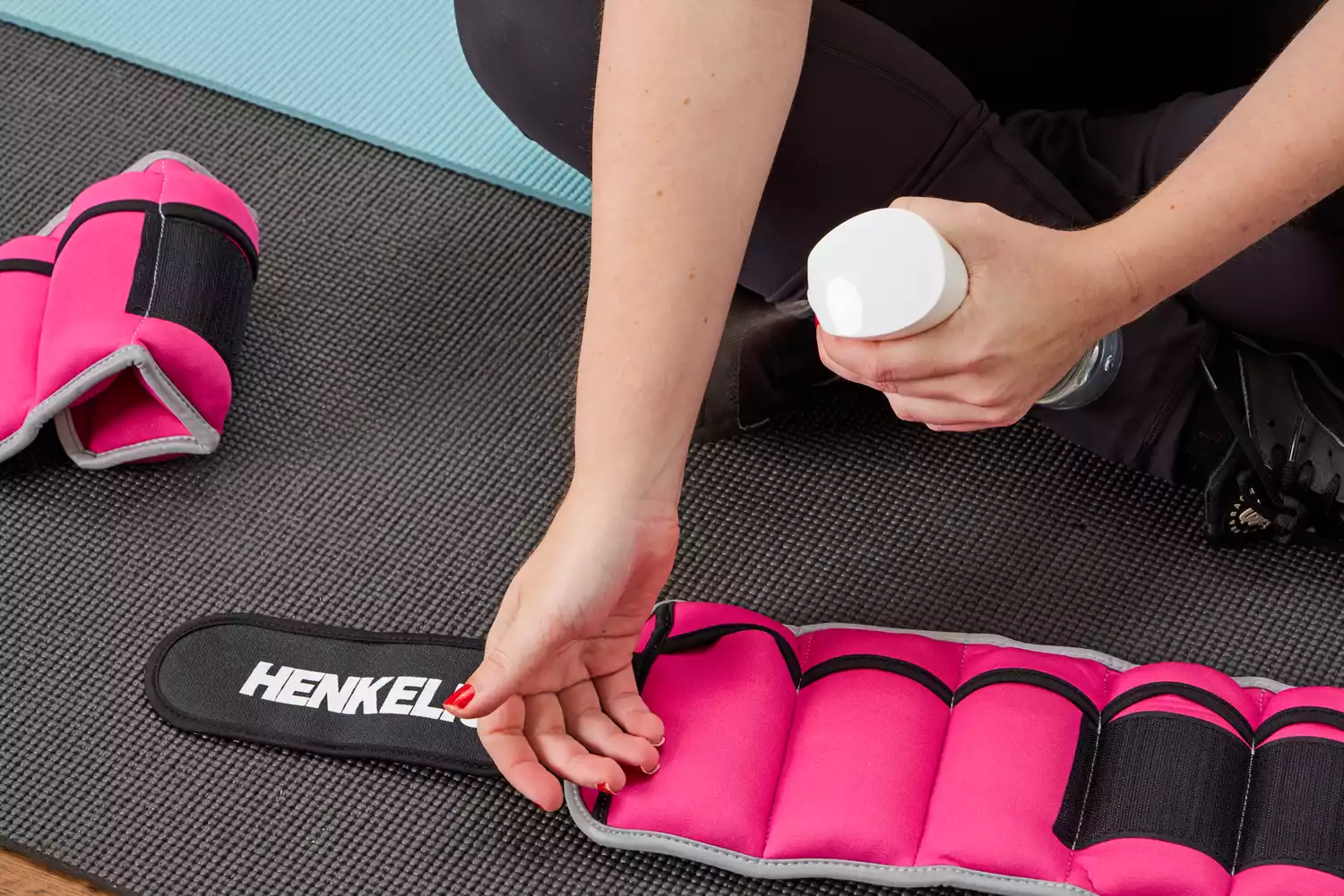 A person sprays their wrist before putting on the Henkelion Adjustable Ankle Weights