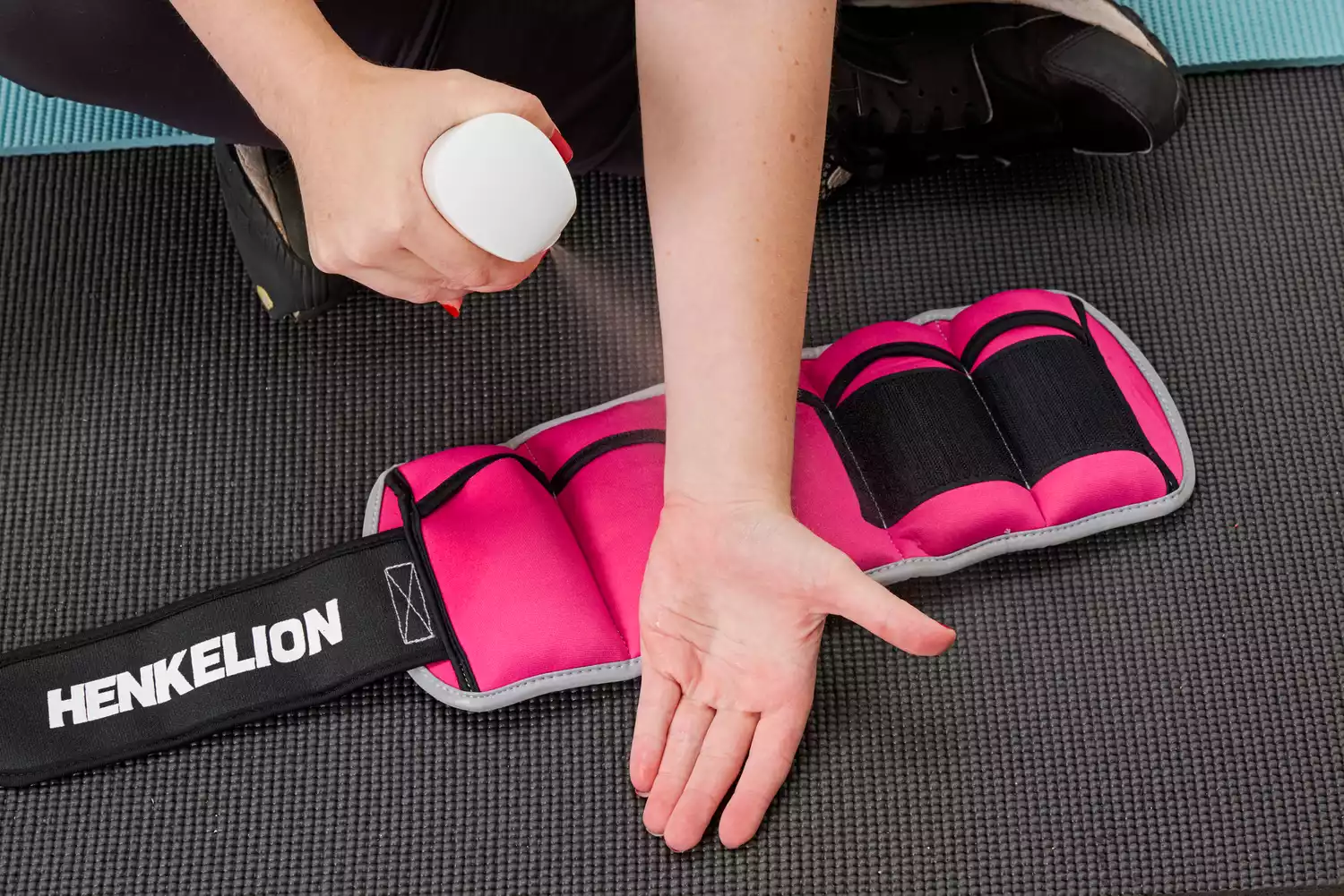 A person sprays their wrist with water before putting on the Henkelion Adjustable Ankle Weights