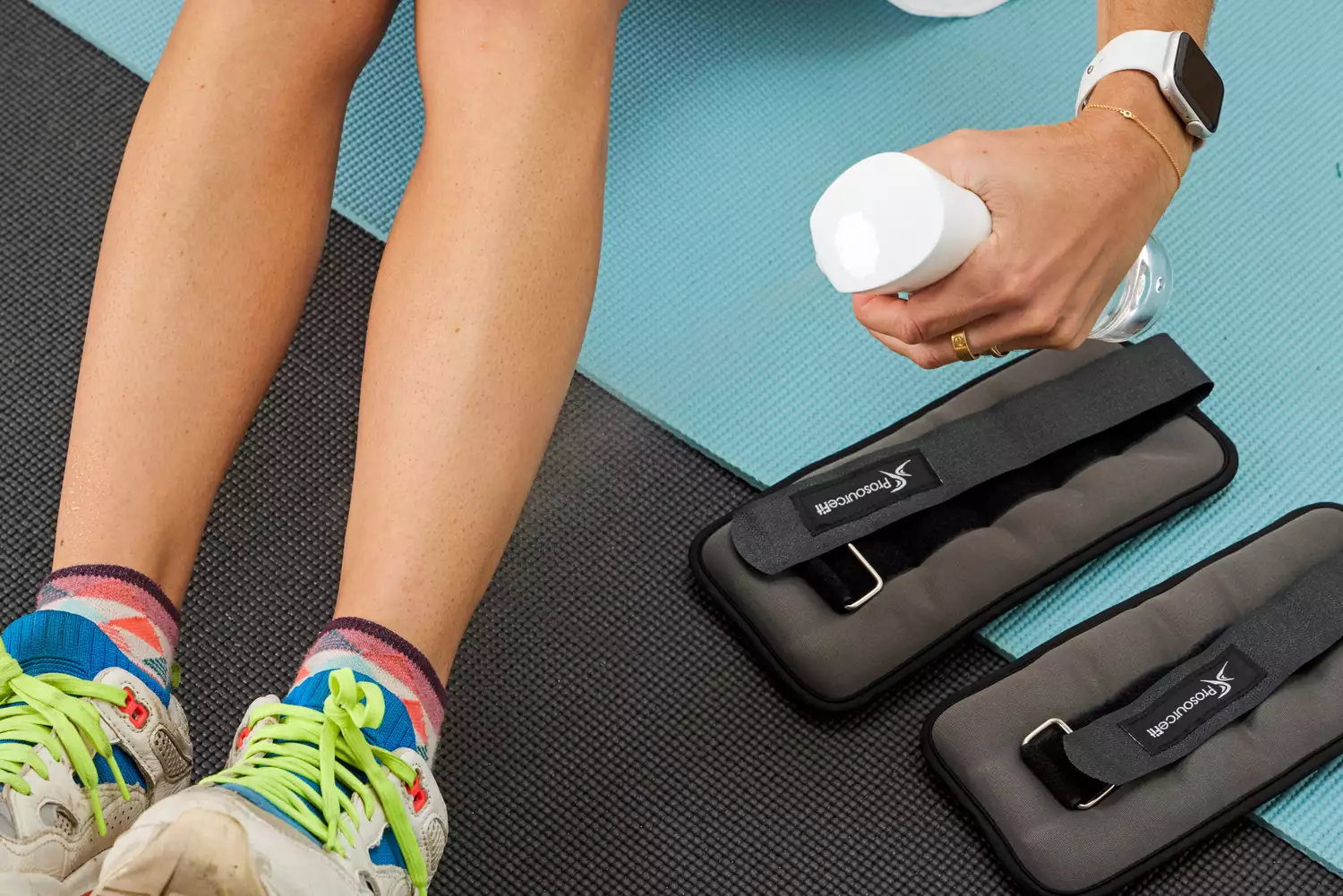 A person sprays their legs with water before putting on the ProsourceFit Ankle/Wrist and Arm/Leg Weights