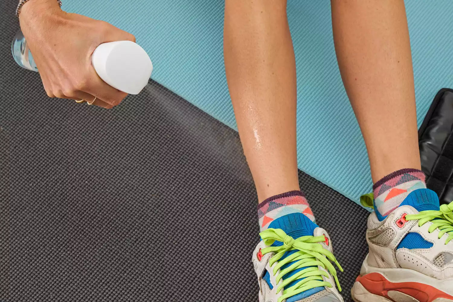 A person sprays water onto their leg before putting on the Tracy Anderson UWRAPS Vegan Leather Ankle/Wrist Weights