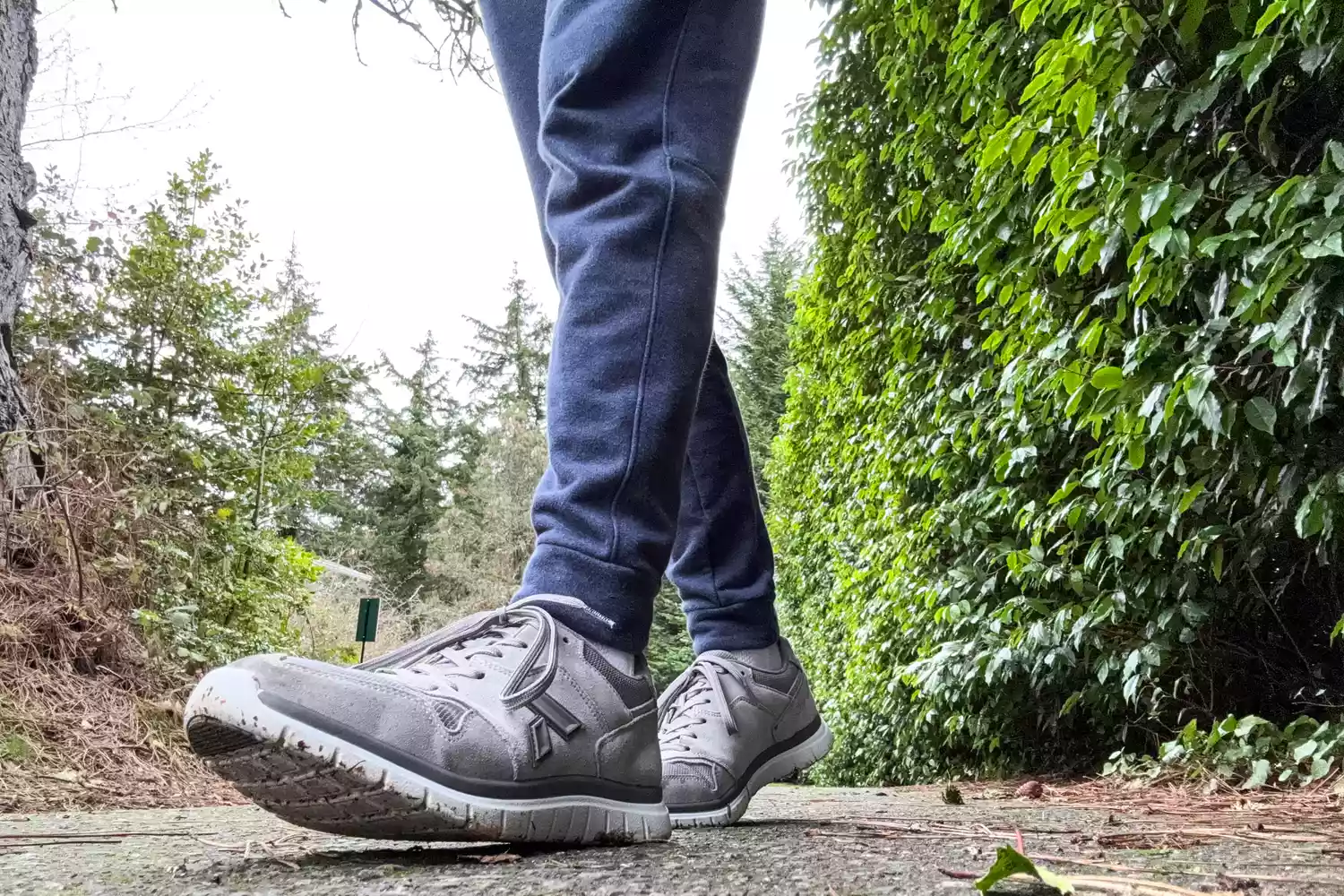 A close-up of two feet walking on a dirt road while wearing the Anodyne No. 50 Men's Sport Trainers